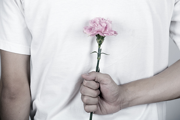 pink carnation hiding behind of man