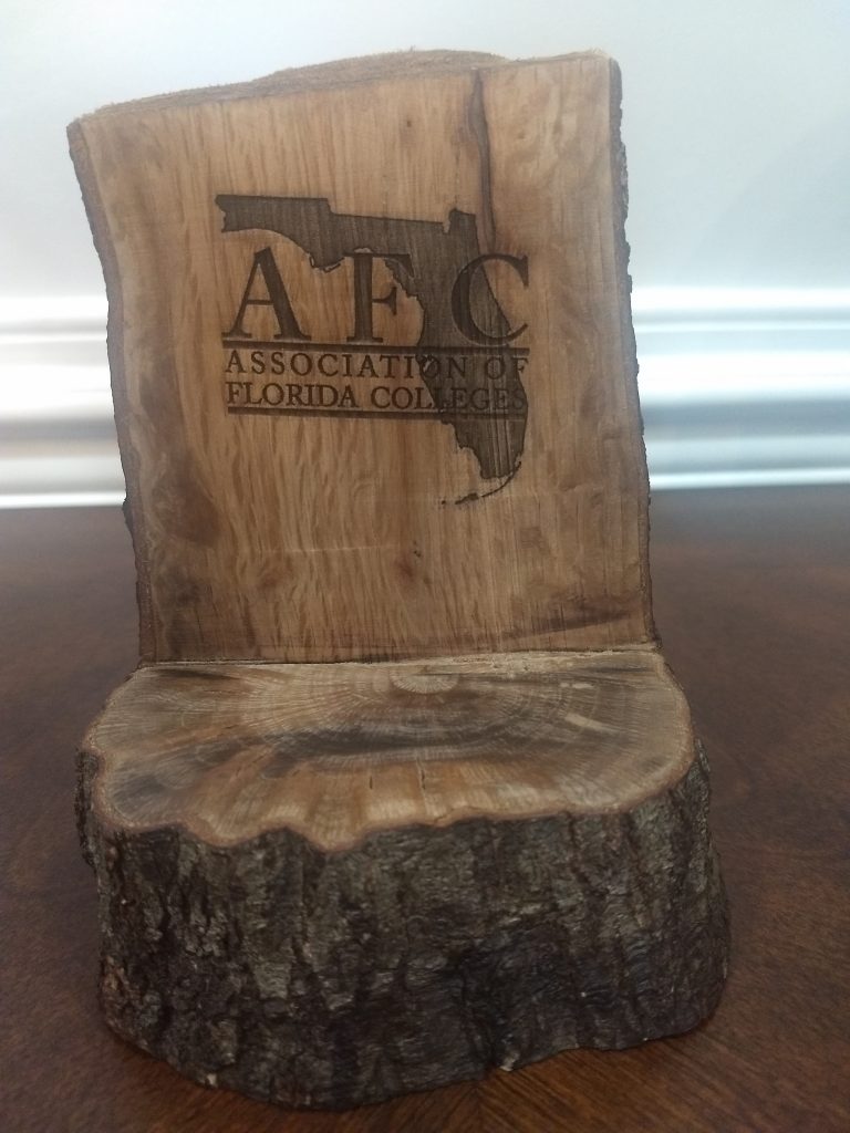 A wood plaque with the Association of Florida Colleges logo on it.