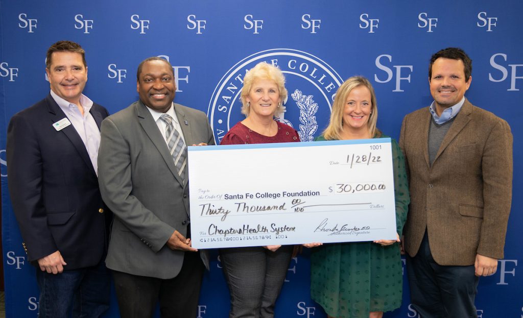 Santa Fe College President Paul Broadie, AVP for Advancement John Hooker stand with members of Chapters Health System with a grant check for $30,000