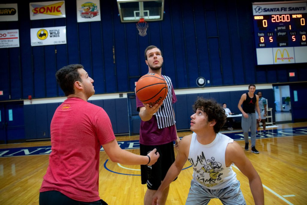 Two players prepare to jump for the ball to determine possession of the basketball during an intermural game at the Santa Fe College Gym.