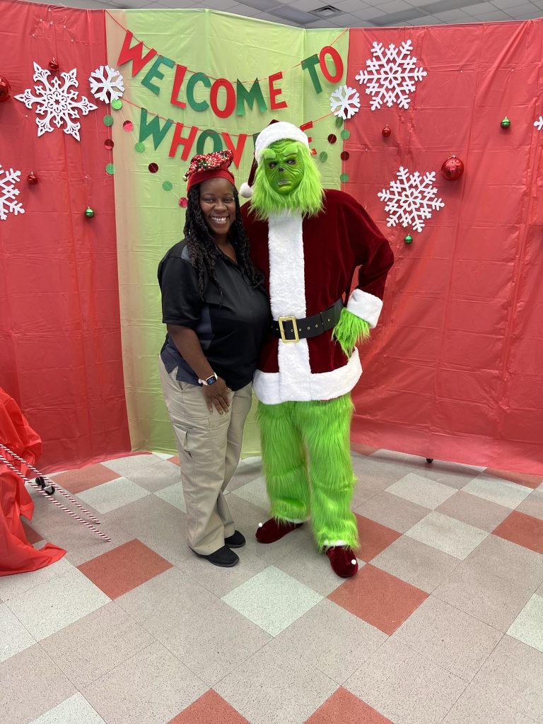 Santa Fe College employees posing with the Grinch at a holiday party event.