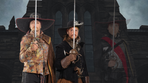 Three actors posing as sword-wielding musketeers.