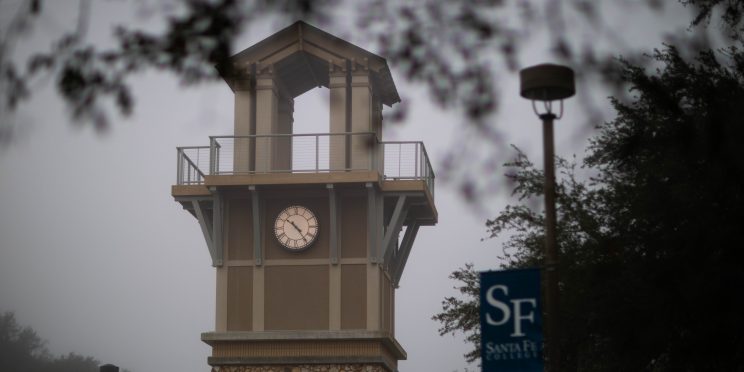 The Santa Fe College clocktower with a pole banner reading "SF Santa Fe College" on the right