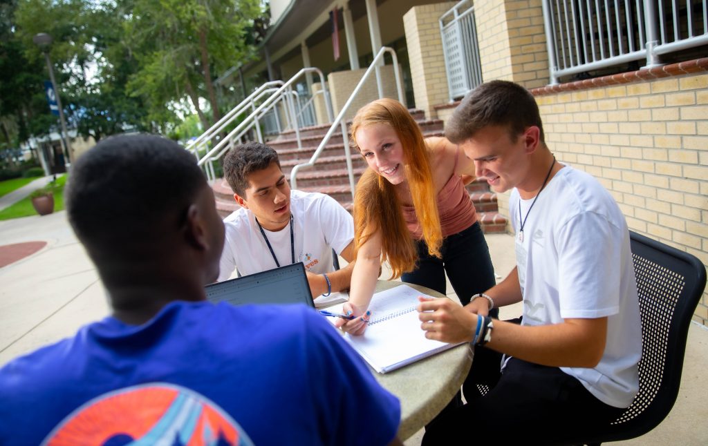 Four students study and hang out in front of the Lawrence W. Tyree Library at Santa Fe College