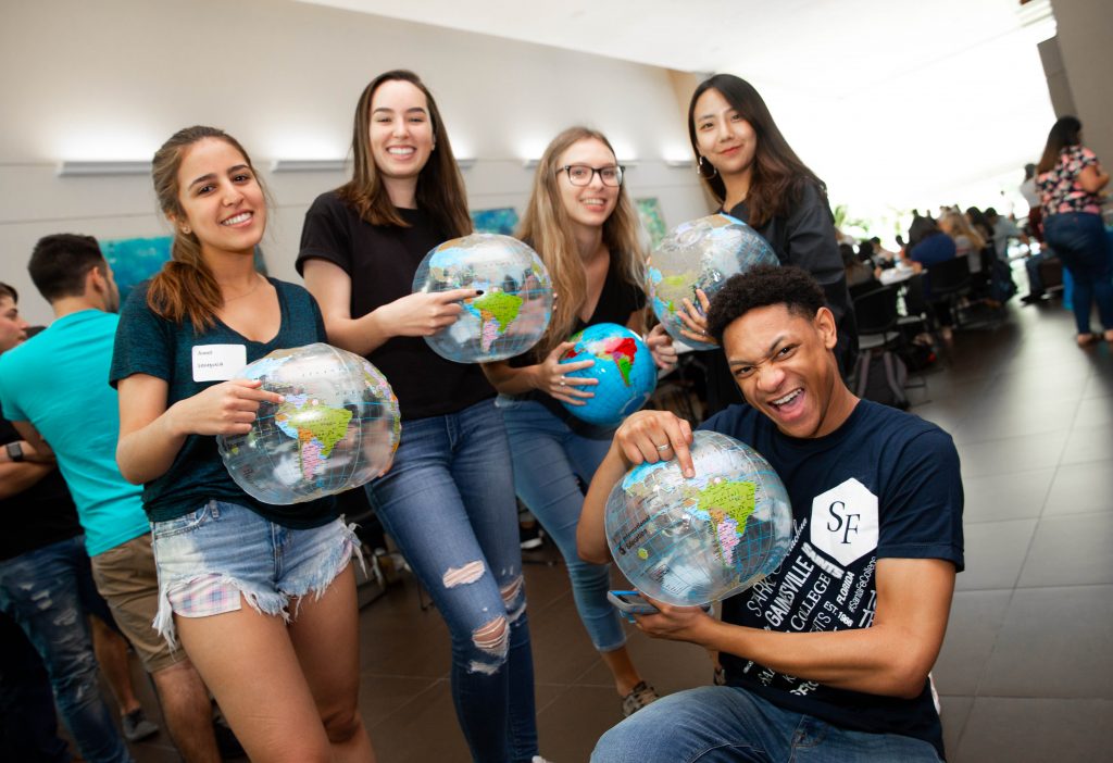 Students point to where they're from on an inflatable globe during the orientation for new International students at the Santa Fe College Fine Arts Hall 