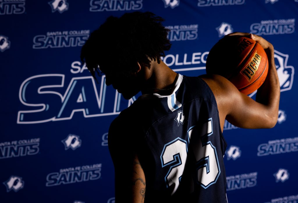 Santa Fe College Saints Men’s Basketball player Ashton Lovette holds a basketball on their right shoulder with their back to the camera