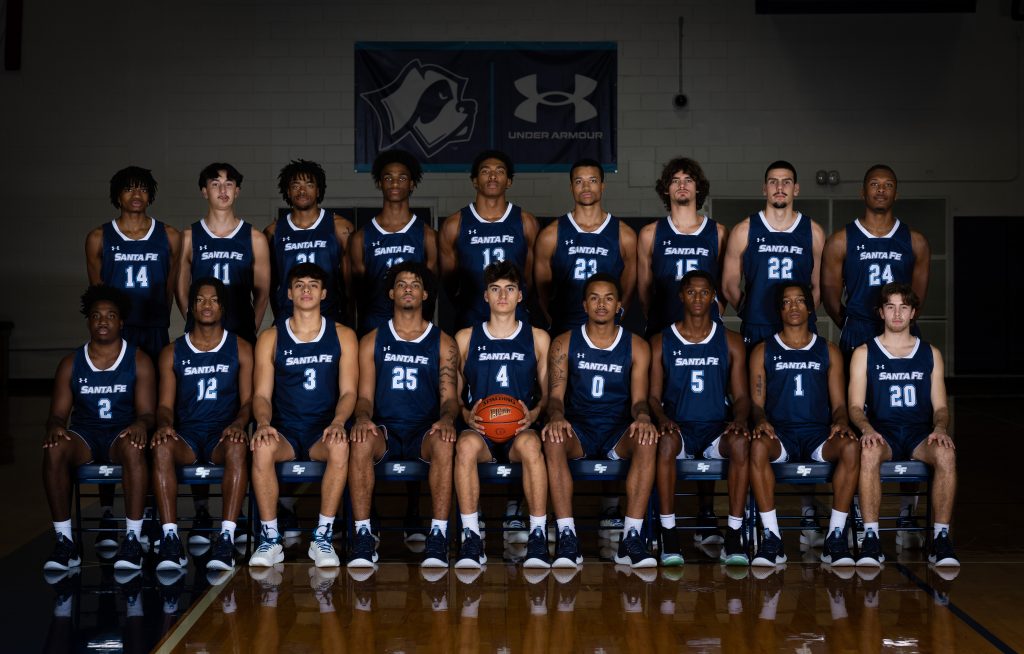 The Santa Fe College Saints Men’s Basketball Team poses in the gym for a group photo. The back row is standing while the front row sits.