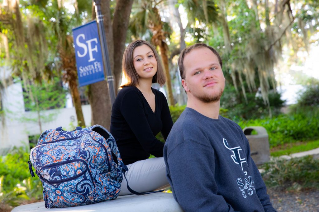 Two people sitting outside looking at the camera at Santa Fe College's Northwest Campus.