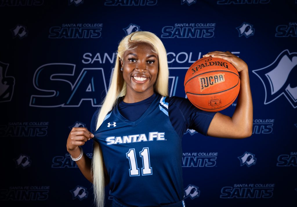 Santa Fe College Saints Women’s Basketball player Leyah Houston holds a basketball on her shoulder.