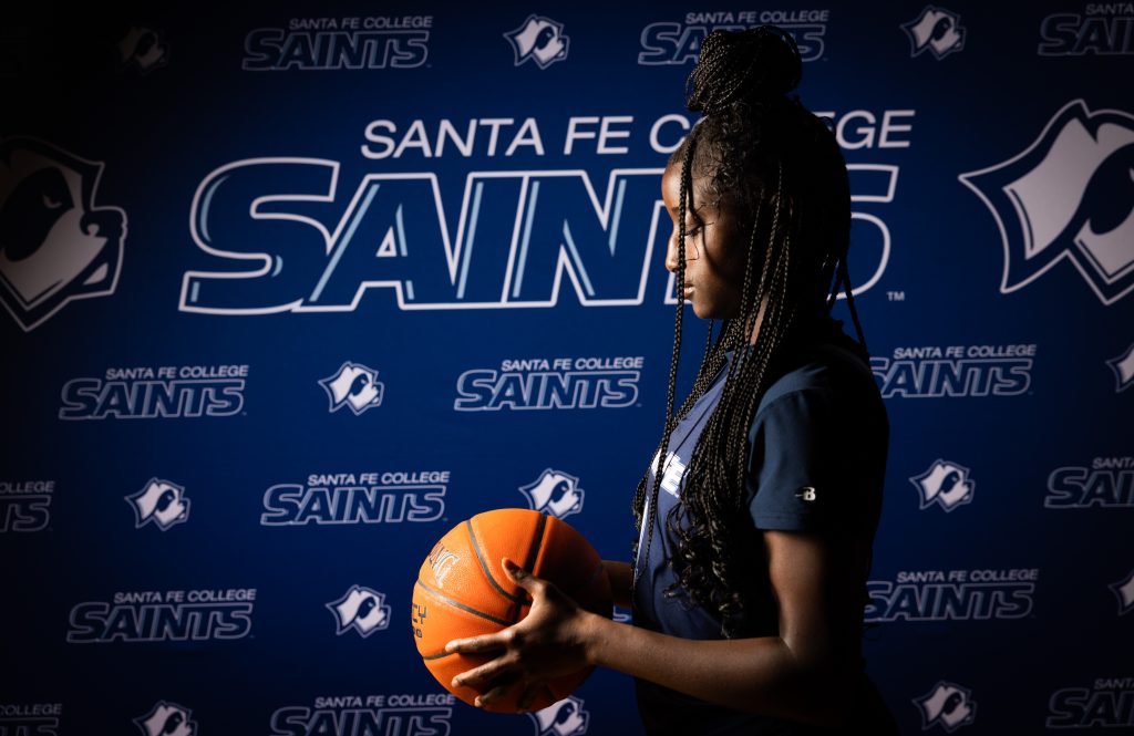 Santa Fe College Saints Women’s Basketball player Aissa Diallo looks down at the basketball in their hands.