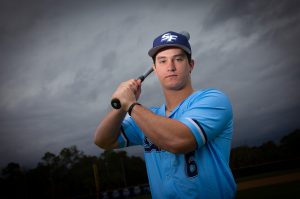 Santa Fe College Saints Baseball player Grant Gallagher holds a baseball bat on his shoulder while he looks into the camera.