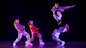 Four dancers perform on stage.