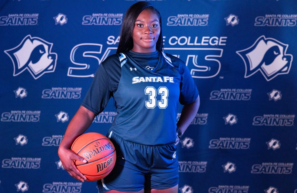 Santa Fe College Saints Women’s Basketball player TaNiya Walker holds a basketball against her leg while posing for a photo.