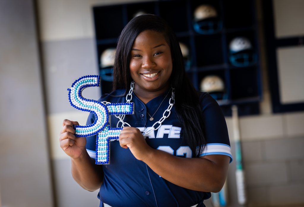 Santa Fe College Saints Softball player Ariana Wright smiles while holding up the letters "SF."