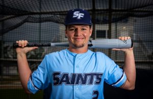 Santa Fe College saints Baseball player Drake Harman holds a baseball bat across his shoulders.
