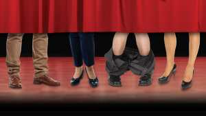 A group of people's legs and feet under a red curtain.