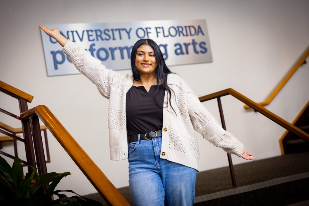 Santa Fe College graduate and University of Florida student Rafa Hossain holds her arms wide in front of a sign that reads, "University of Florida Performing Arts."