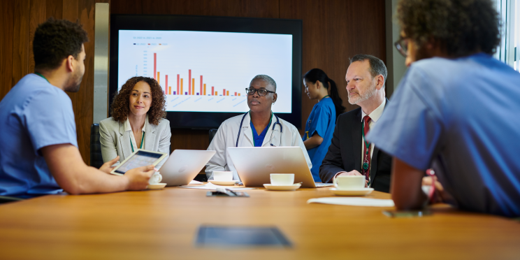 Medical professionals and an executive discussing data in a conference room.