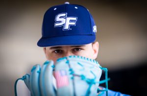 Santa Fe College Saints Baseball player Macklin Miller holds their mitt in front of the bottom half of their face.