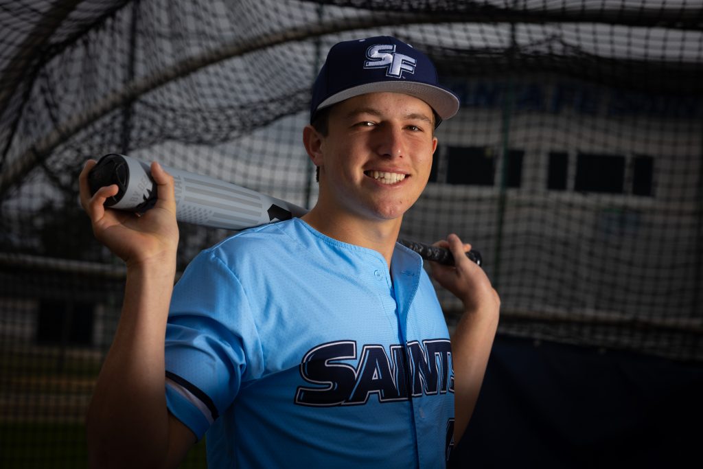 Santa Fe College Saints Baseball player Trey Freeman holds a baseball bat across his shoulders.