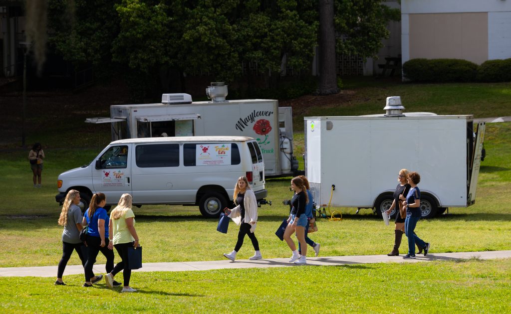 A group of people walking through the Oak Grove.